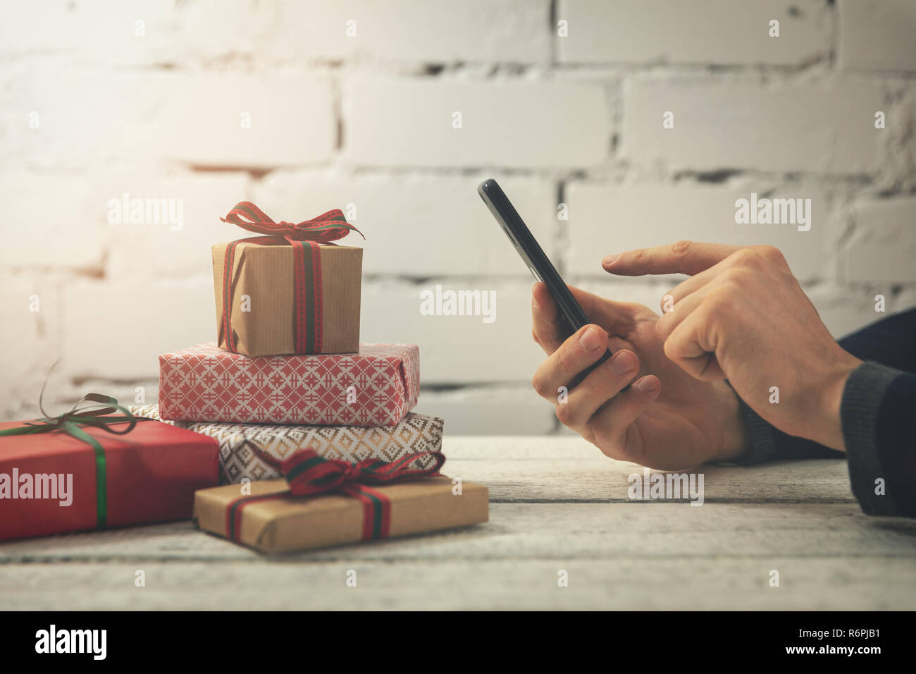 Mann mit Smartphone Geschenke online kaufen im Internet speichern Stockfoto