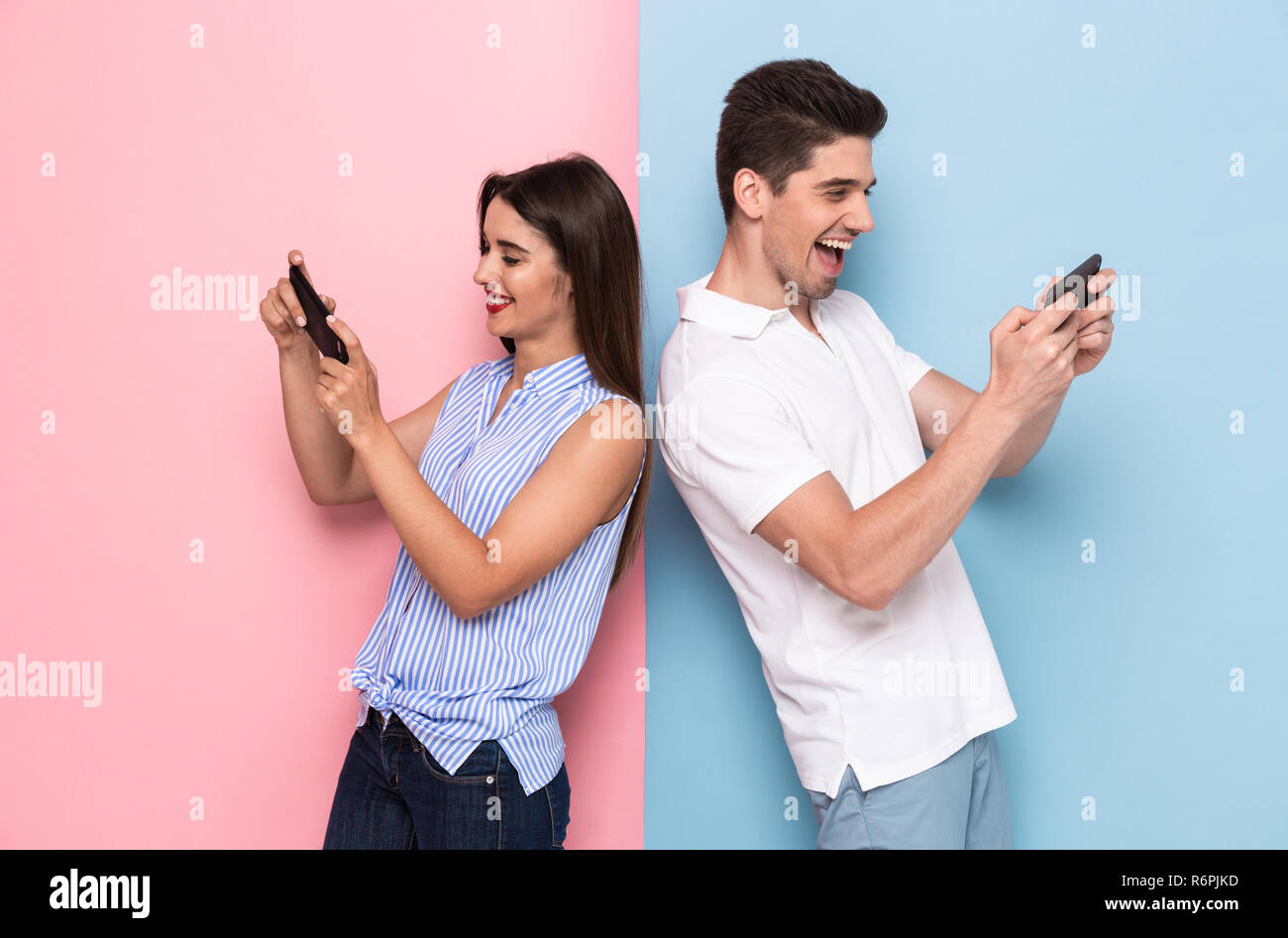 Junger Mann und Frau zusammen spielen Videospiele über Telefone über bunte Hintergrund isoliert Stockfoto