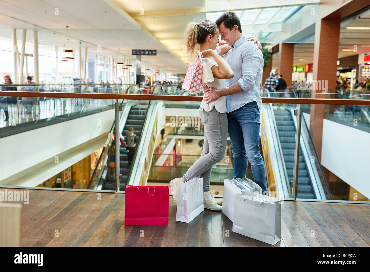 Paar in Liebe im Einkaufszentrum mit vielen Einkaufstüten flirten Stockfoto