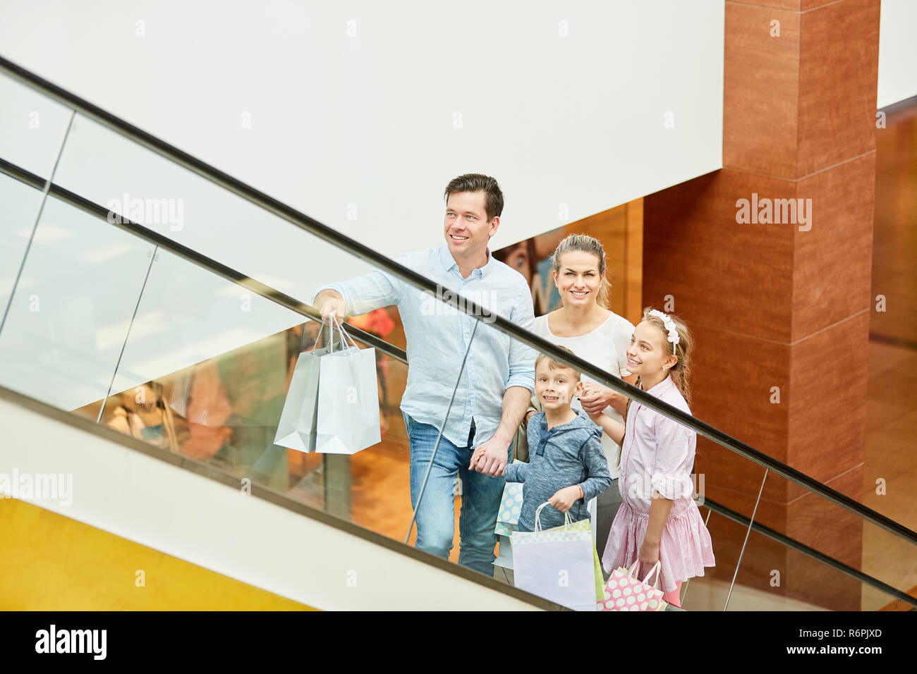 Glückliche Familie und zwei Kindern auf einer Rolltreppe im Einkaufszentrum Stockfoto