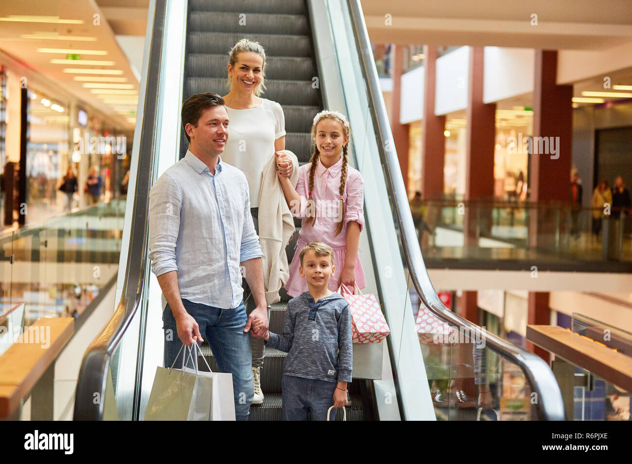 Familie und zwei Kindern auf einer Rolltreppe während der Einkauf am Mall Stockfoto