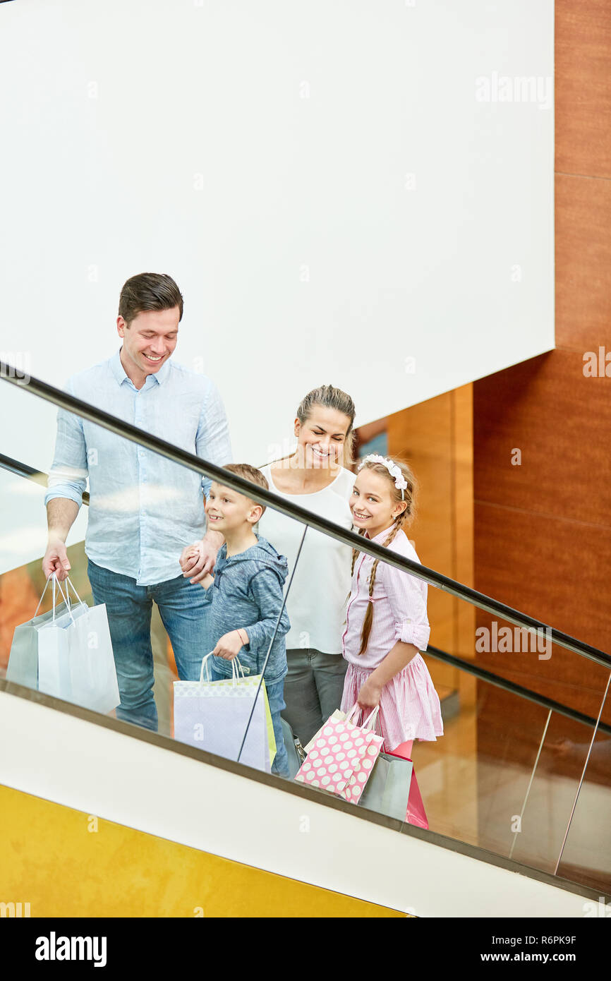 Familie mit zwei Kindern auf einer Rolltreppe beim Shopping in der Mall Stockfoto