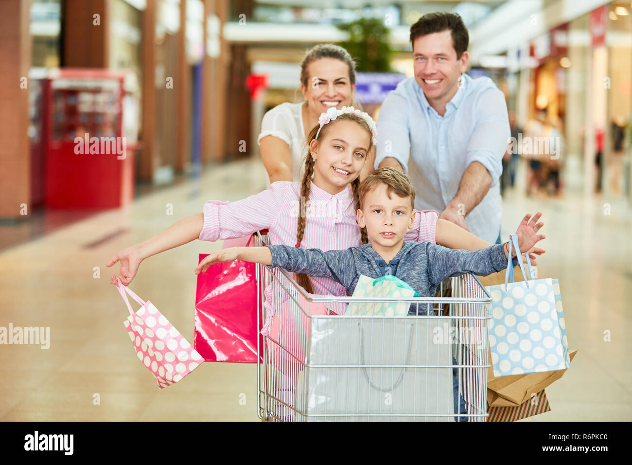 Eltern und Kinder Shopping im Warenkorb haben Spaß im Einkaufszentrum Stockfoto