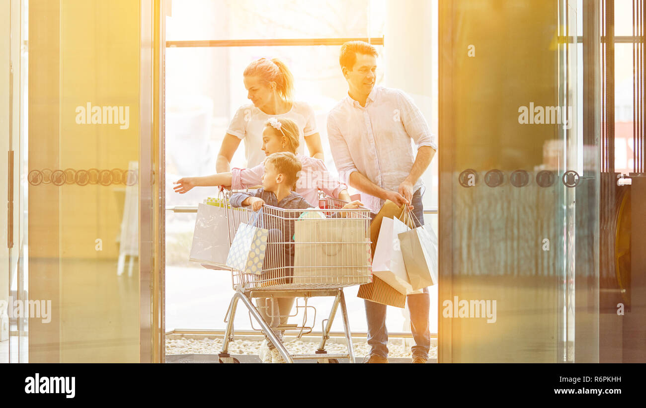 Familie schiebt zwei Kinder im Warenkorb beim Shopping in der Mall Stockfoto