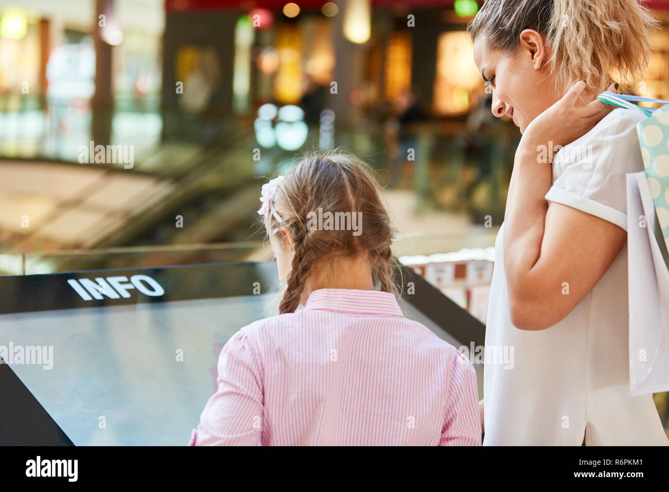 Familie ist auf der Suche nach Shops auf dem Touchscreen Informationen Kiosk im Einkaufszentrum Stockfoto