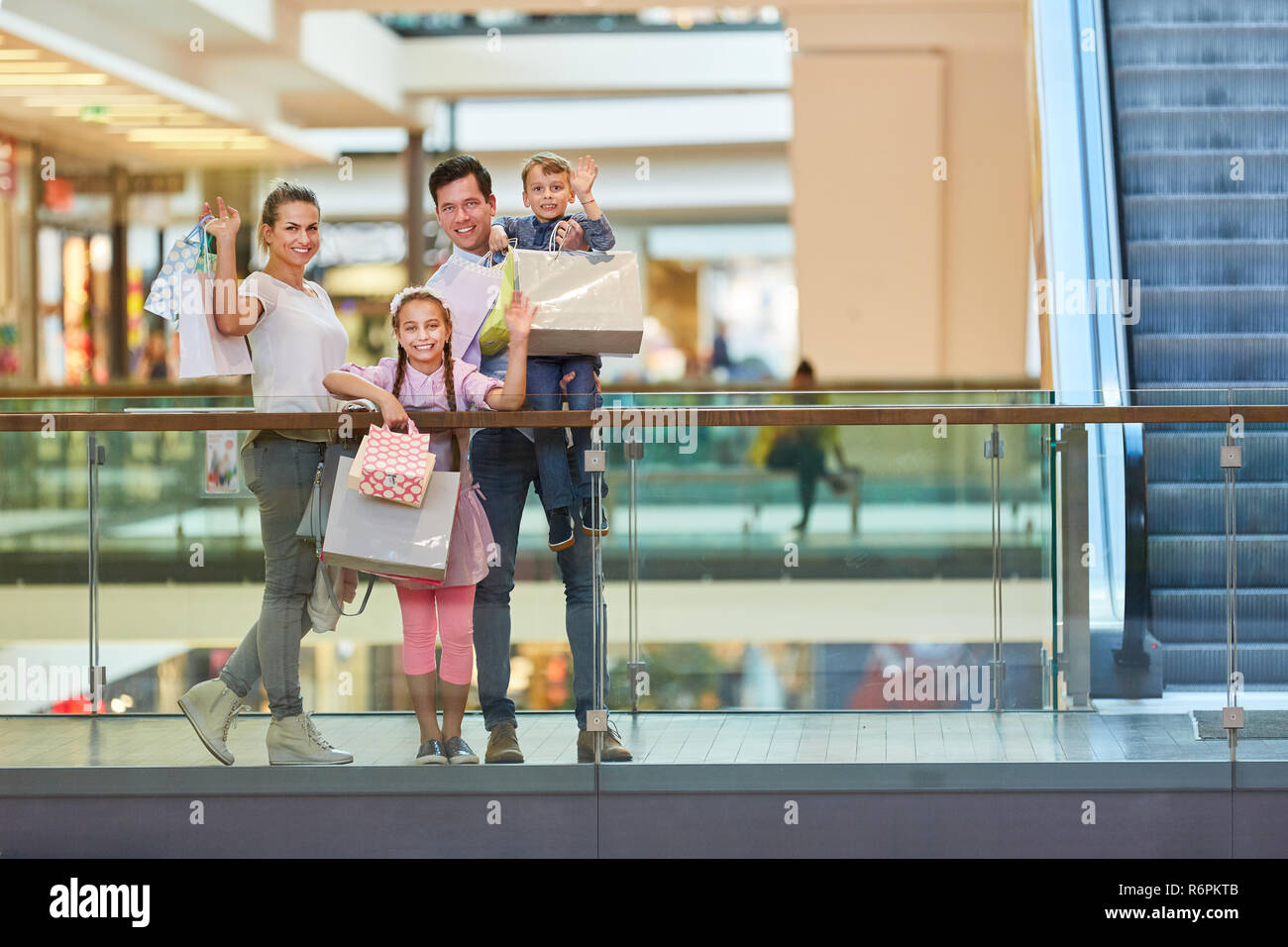 Eltern und zwei Kindern winkend Einkaufstaschen an der Shopping Mall Stockfoto
