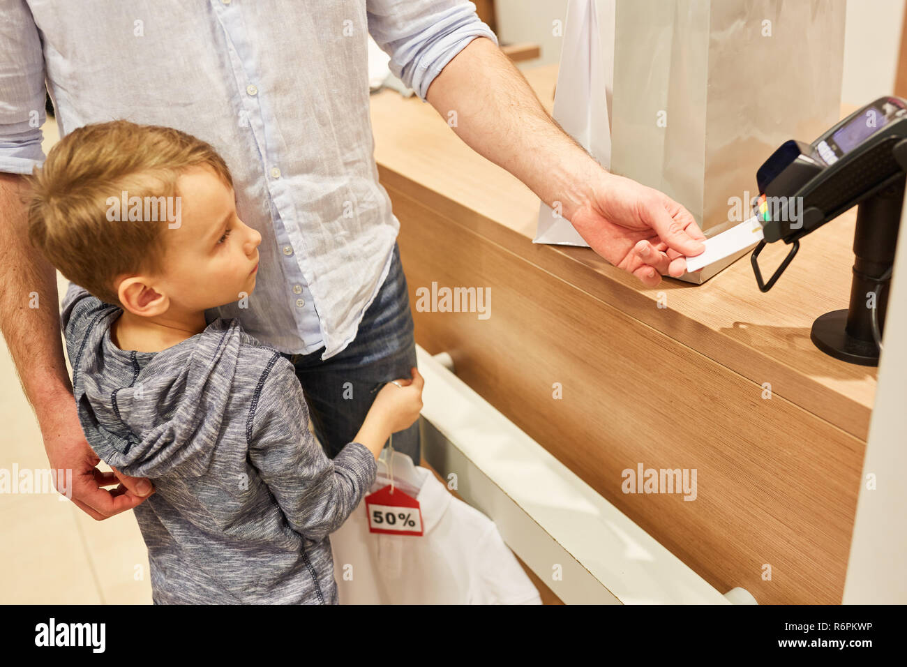 Vater und Kind bezahlen per Kreditkarte oder Kundenkarte an der Card Terminal Stockfoto