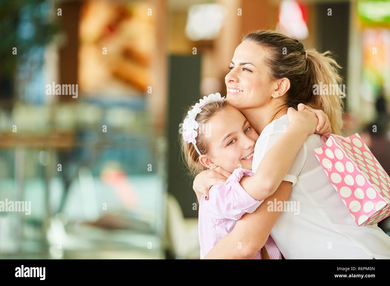 Tochter und Mutter Grüßt einander mit einer Umarmung während des Einkaufs Stockfoto
