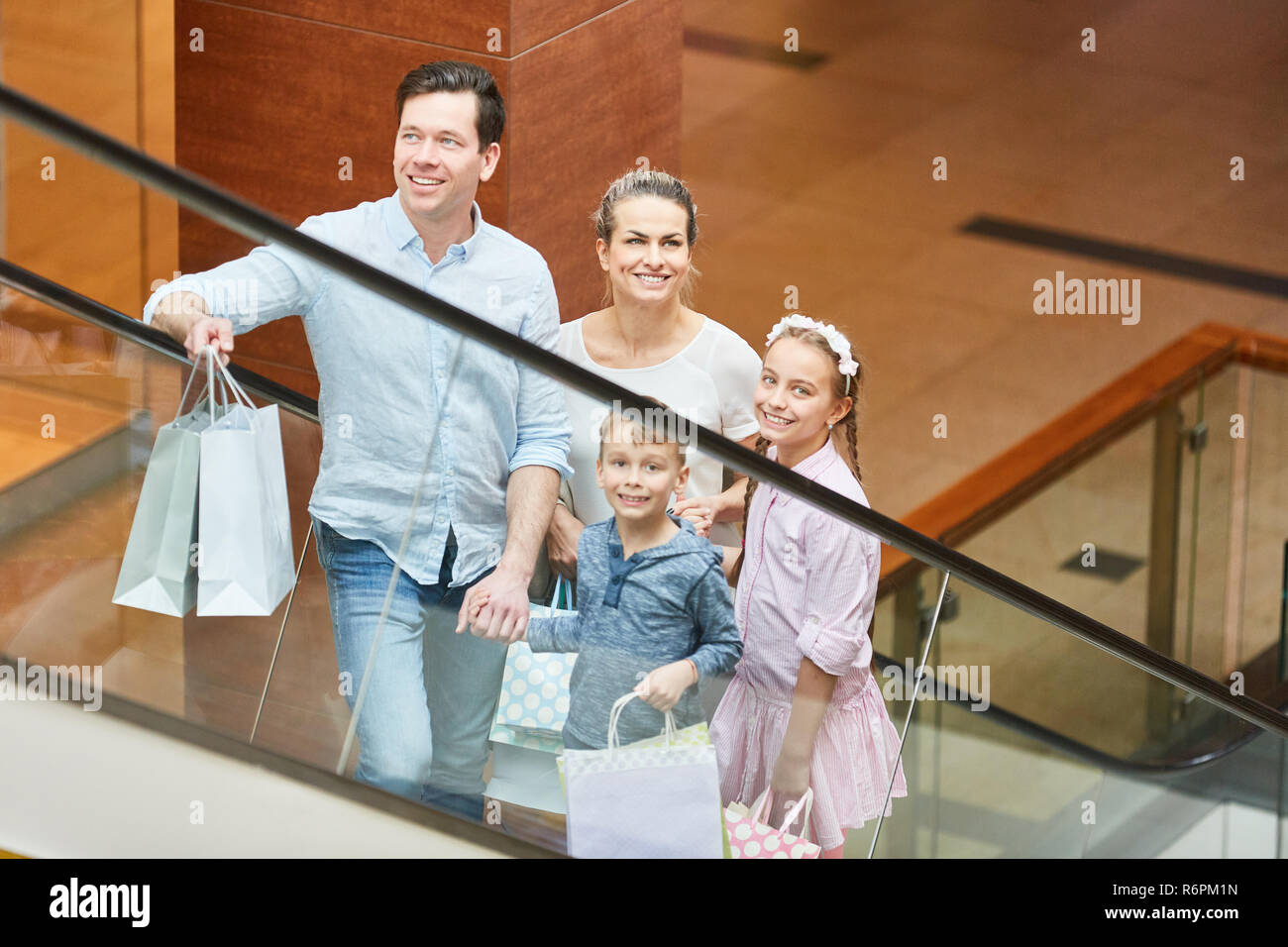 Glückliche Familie mit zwei Kindern Fahrten eine Rolltreppe im Einkaufszentrum Stockfoto