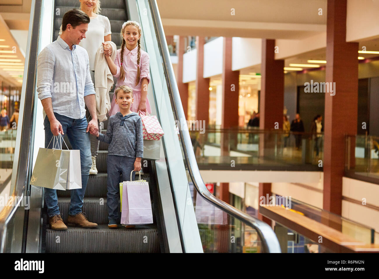 Familie und zwei Kinder fahren auf einer Rolltreppe im Einkaufszentrum Stockfoto