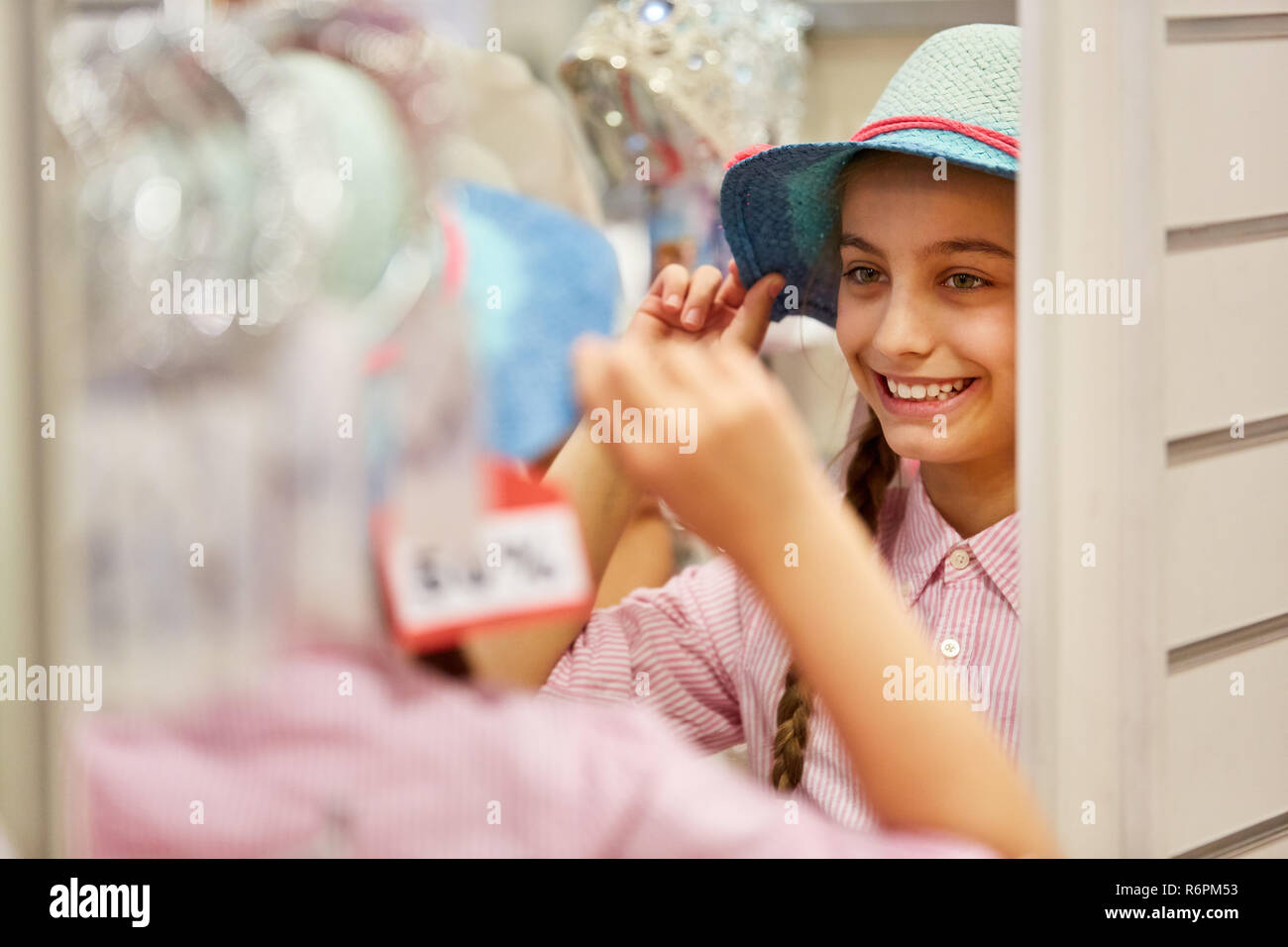 Mädchen am Hut kaufen in den Fitting in einer Boutique im Einkaufszentrum Stockfoto