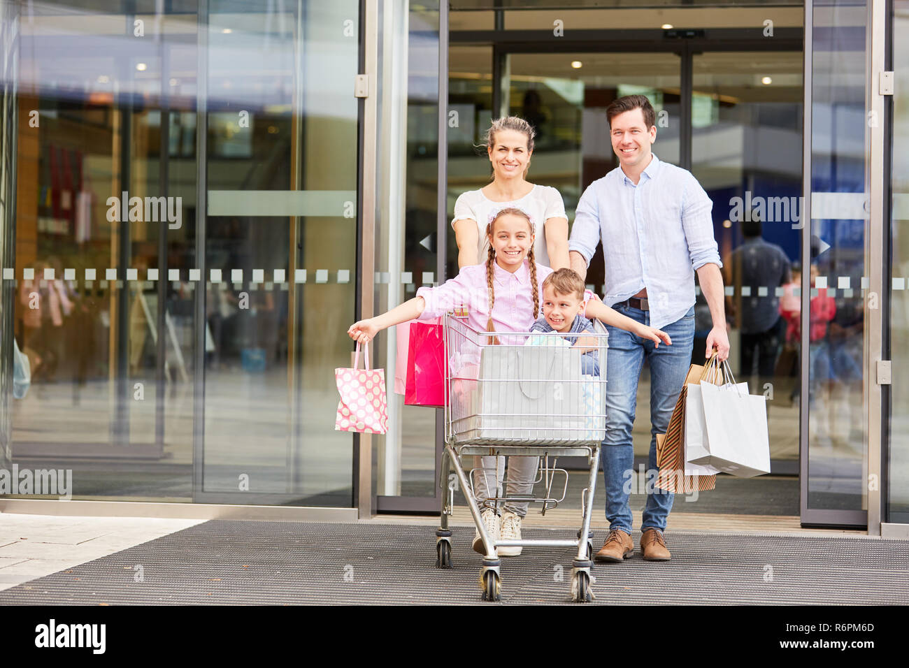 Happy Family nach dem Einkaufen mit Warenkorb und Einkaufstaschen Stockfoto