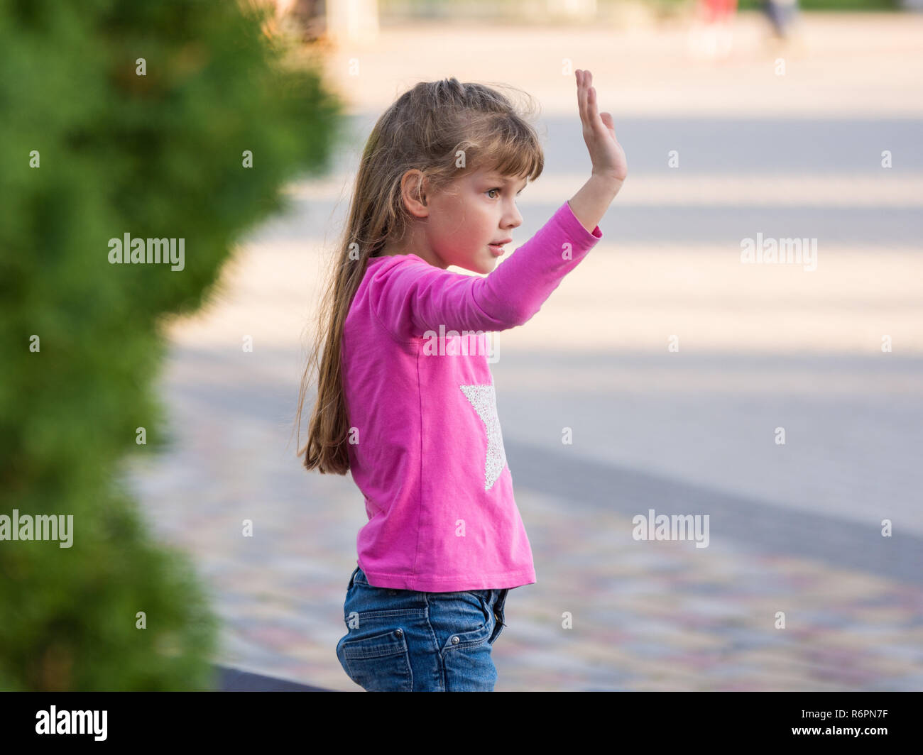 6-jähriges Mädchen seine Hand winken, Seitenansicht Stockfoto