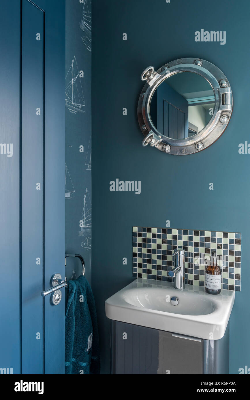 Bullaugen Spiegel über kleine Waschbecken mit Fliesen- Anti-siphon in Hampshire Mill House von Emma Maler neu gestaltet Stockfoto