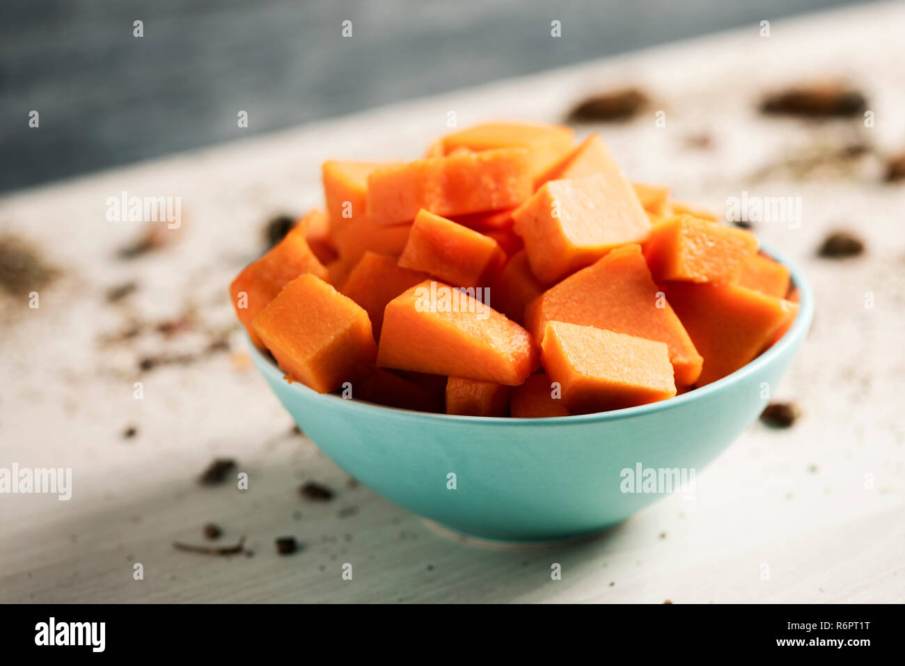 Nahaufnahme von einem Stapel von gehackten rohen Kürbis in einem blassen Grün Schüssel auf einen hölzernen Tisch Stockfoto