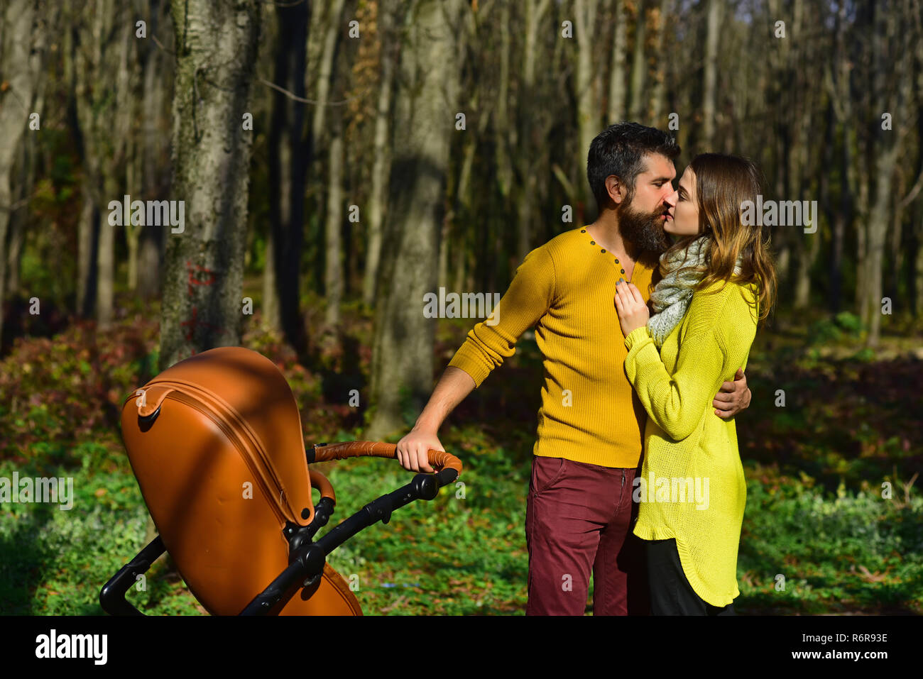 Liebevoller Ehemann kuss Frau im Park. Familie Paar mit Baby Kinderwagen Kuss auf sonnigen Außenpool. Lebe ein Leben, das sie lieben Stockfoto