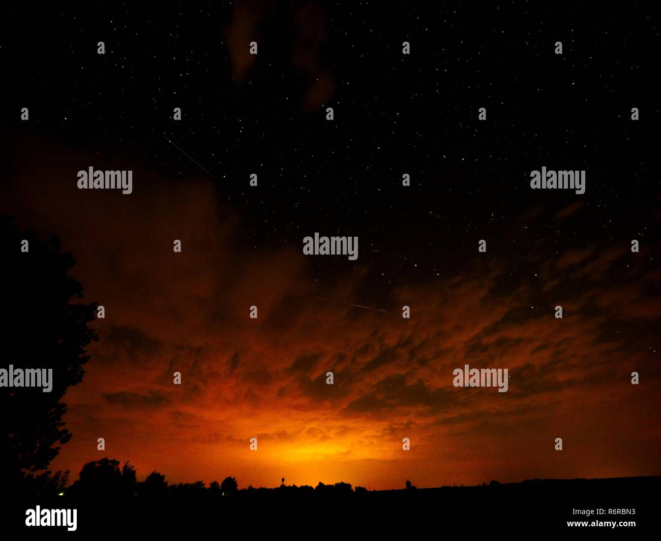 Ein reichhaltiges rot-orange strukturierte Trübung, die sich vom Horizont zu einem halben Himmel. Die verbleibende Hälfte der Himmel klar ist, dunkel mit Sternen. (CTK Photo Stockfoto