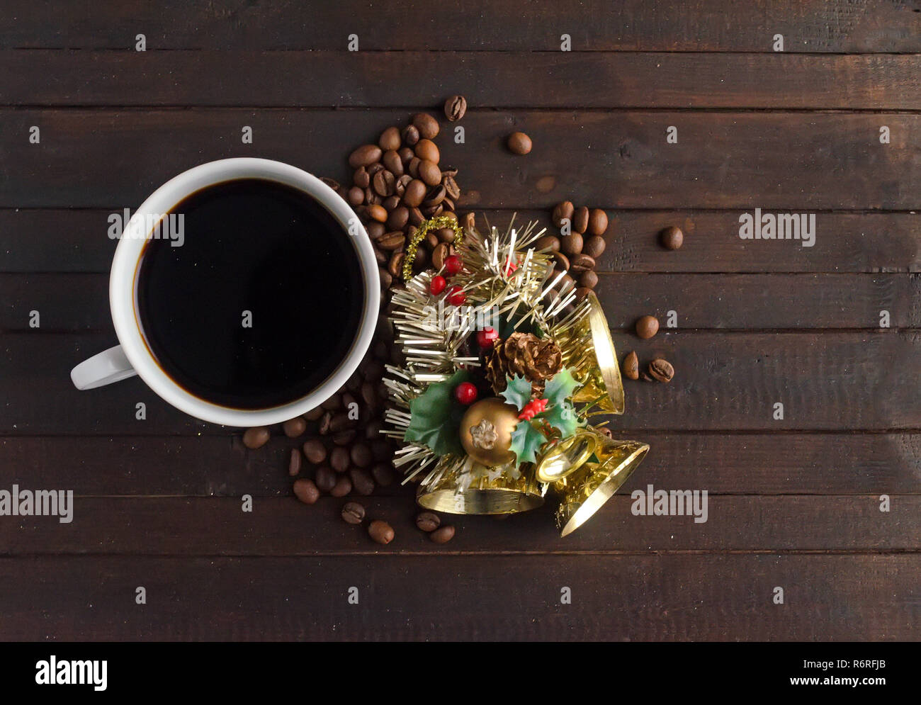 Eine Tasse Kaffee, Kaffeebohnen und Weihnachten Spielzeug mit drei goldenen Glocken. Stockfoto
