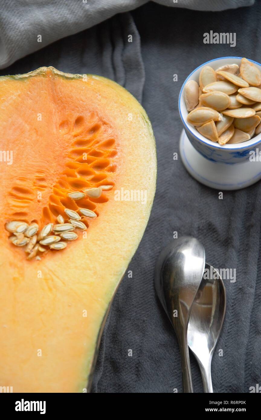 Kürbis in Scheiben geschnitten in der Hälfte auf eine Tabelle mit Samen in einer Tasse. curcubita moschata für das Abendessen vorbereitet Stockfoto