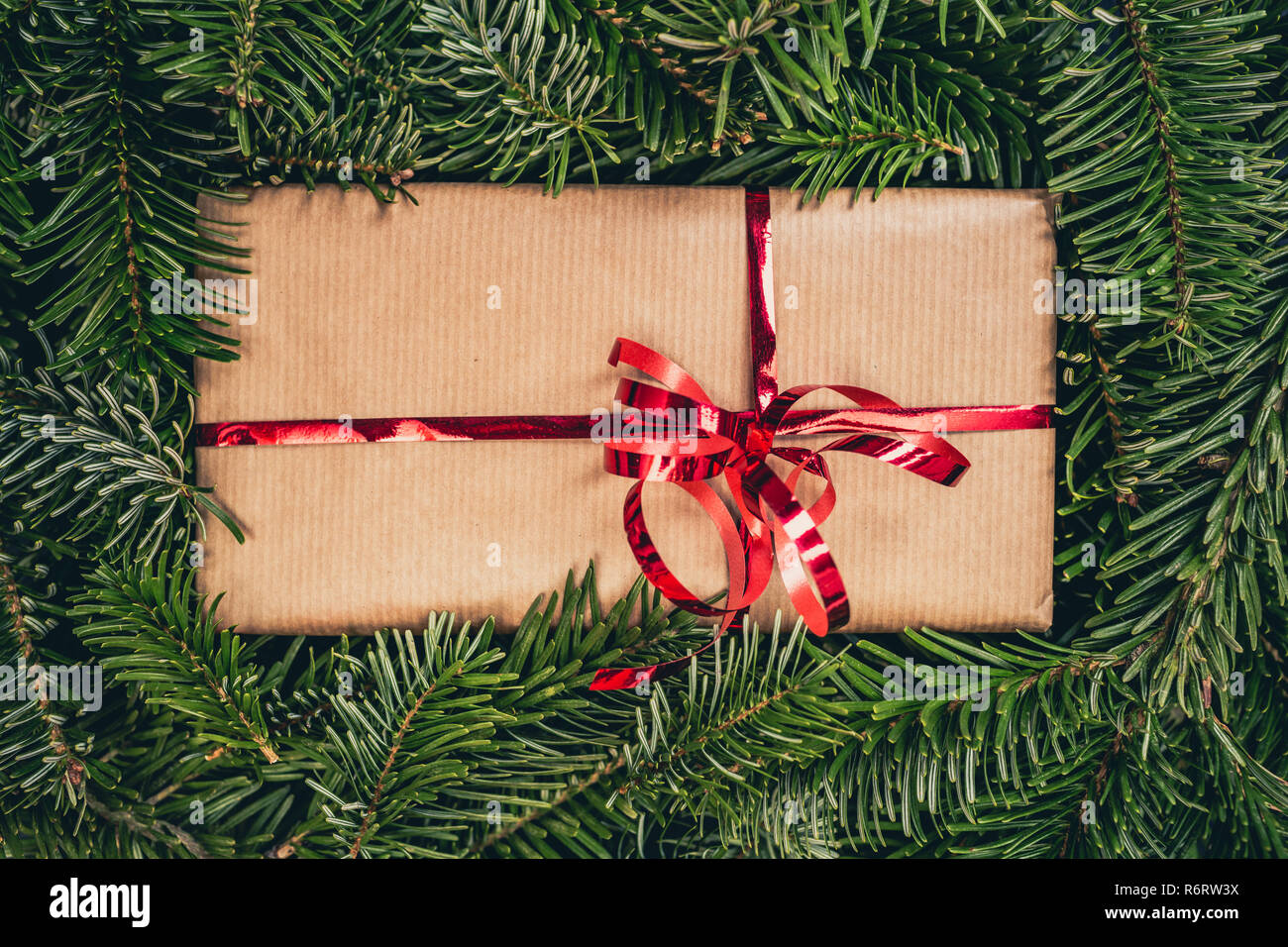 Weihnachten Geschenk auf grünen Kiefer Fichte oder. Vintage rot glänzend Band auf einem Papier Geschenkbox. Top Detailansicht mit kopieren. Stockfoto