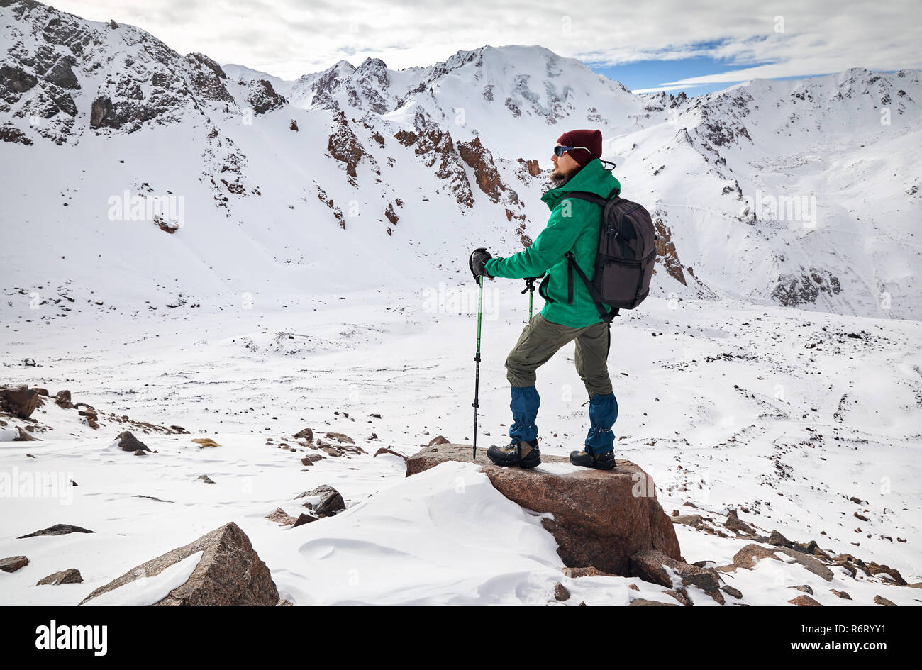 Wanderer mit Trekking und Rucksack auf den Felsen am verschneiten Berge Hintergrund Stockfoto