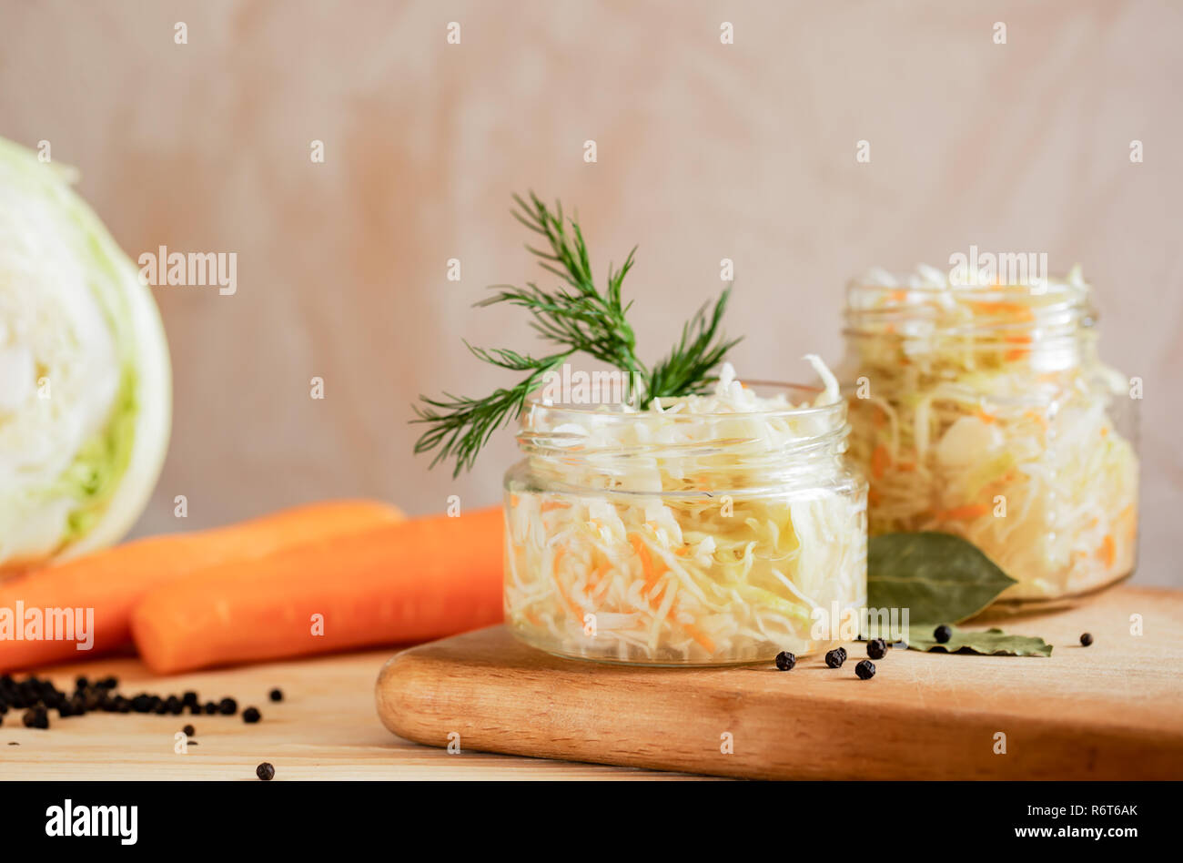 Gläser mit Sauerkraut und Zutaten für die Zubereitung: Kohl und Möhren auf hellen Hintergrund. Stockfoto