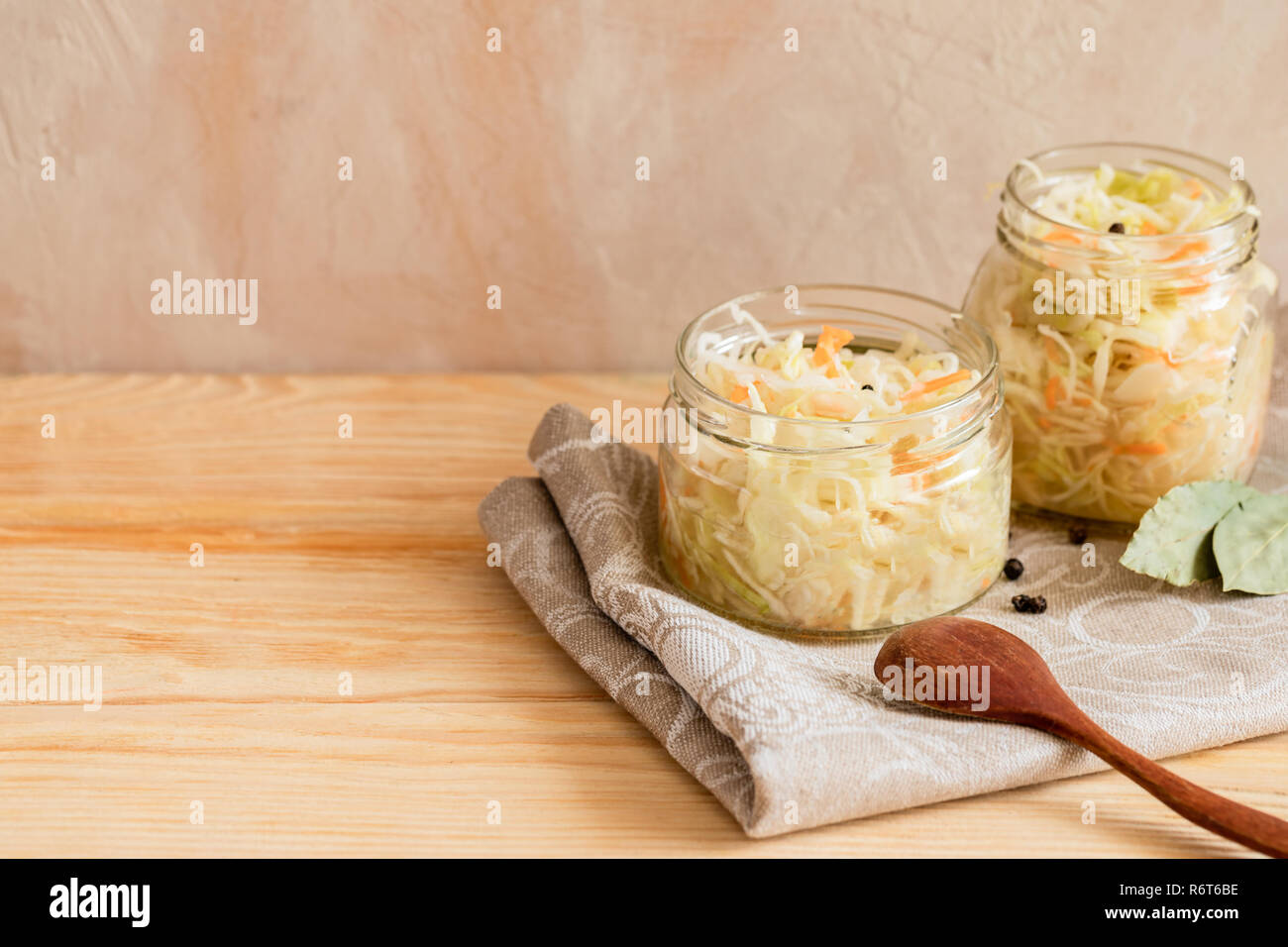 Zwei Gläser mit Sauerkraut auf dem Kochen Handtuch auf Holztisch auf hellen Hintergrund. Stockfoto