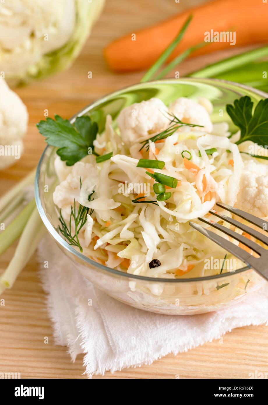 Sauerkraut Salat mit Kräutern in Glasschüssel steht auf dem Tisch und mit der Gabel Zutaten. Stockfoto
