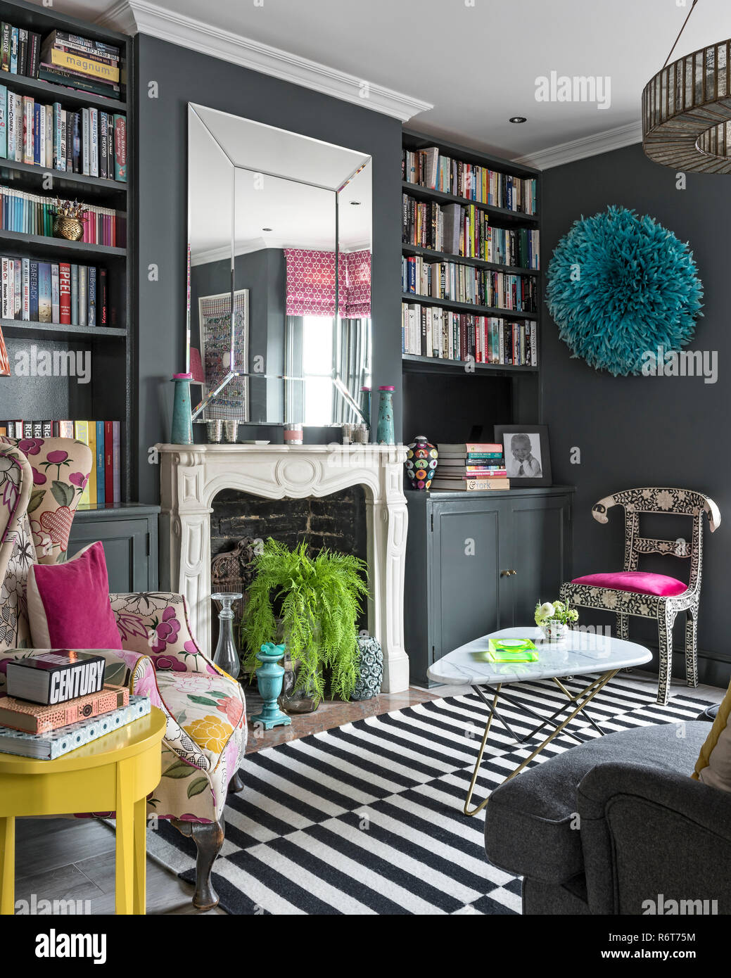 Upcycled wingback Sessel mit großem Spiegel über dem Kamin in Richmond home Stockfoto