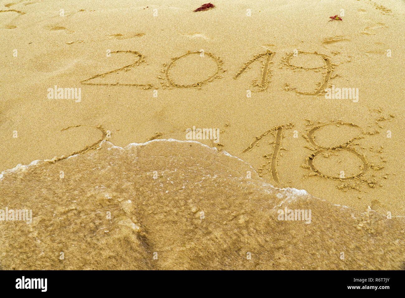 Neues Jahr 2019 kommt Konzept - Inschrift 2018 und 2019 auf einem Strand Sand, ist die Welle, die die Ziffern 2018. Stockfoto