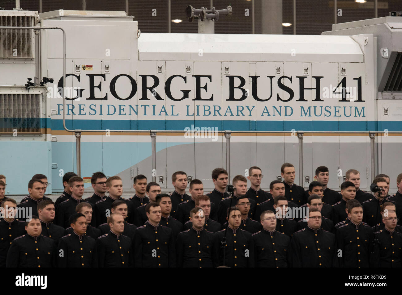 Düstere Mitglieder der Texas A&M University Gesang Kadetten stehen vor der Zug mit den Sarg des ehemaligen Präsidenten George H.W. Bush nach seiner Ankunft aus Houston an der Texas A&M University für die Beerdigung am George Bush Bibliothek auf dem Campus. Stockfoto