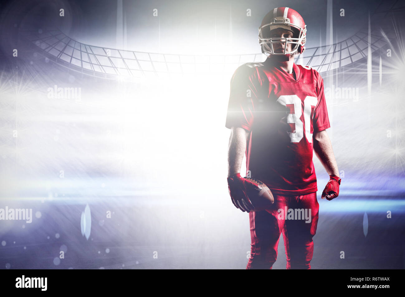 American football player im Helm Holding mit Fußball gegen American football arena Stockfoto