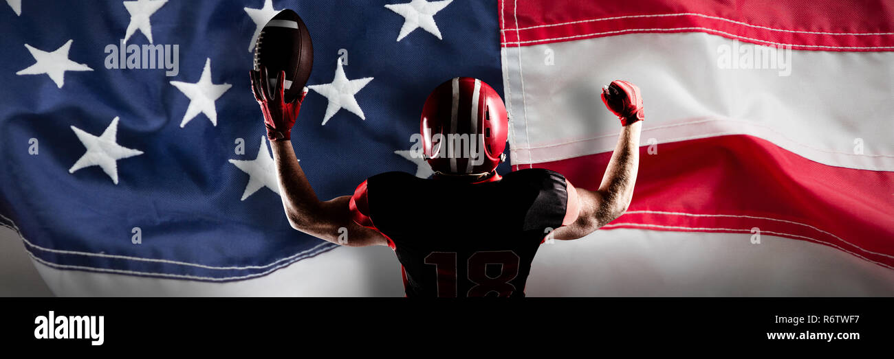 American Football Spieler mit Helm Holding Fußball in der Sieg gegen Full Frame der amerikanischen Flagge Stockfoto