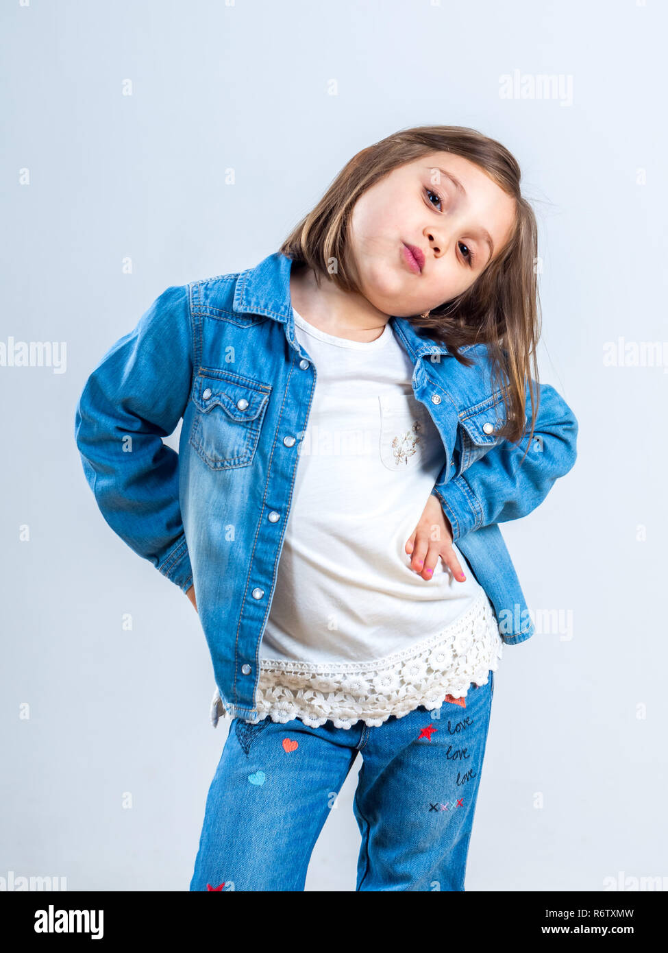 Kleine Mädchen in Jeans für die Kamera posiert im Studio. Stockfoto
