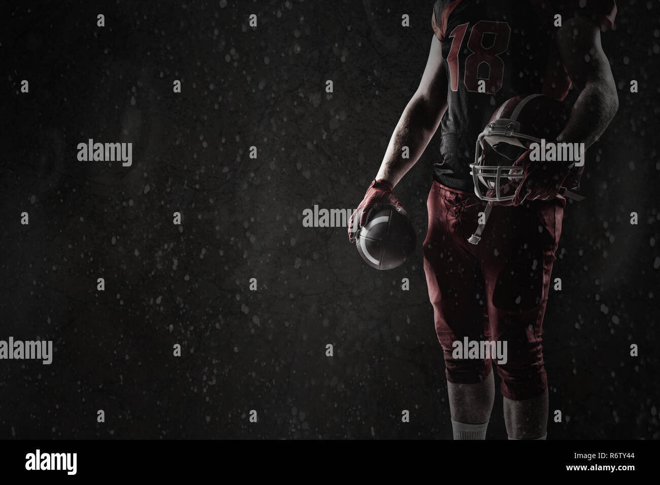 American Football Spieler mit Helm und Rugby Ball gegen alte Wand Hintergrund Stockfoto