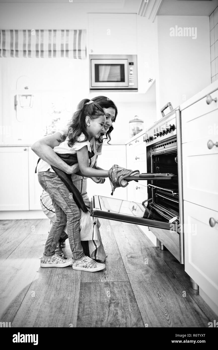 Mutter und Tochter, die Plätzchen in den Ofen stellen Stockfoto