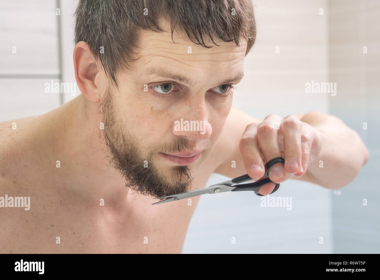 Der Kerl ist eine Schere mit Bart am Kinn Stockfoto