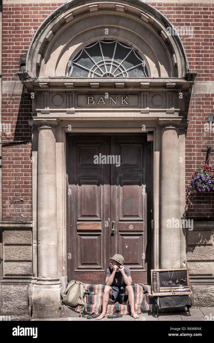 Ein Mann verwendet die Schritte einer stillgelegten Bank seine Produktpalette für kleine Geschenke, die Touristen in die Somerset Stadt Glastonbury zu verkaufen. Stockfoto