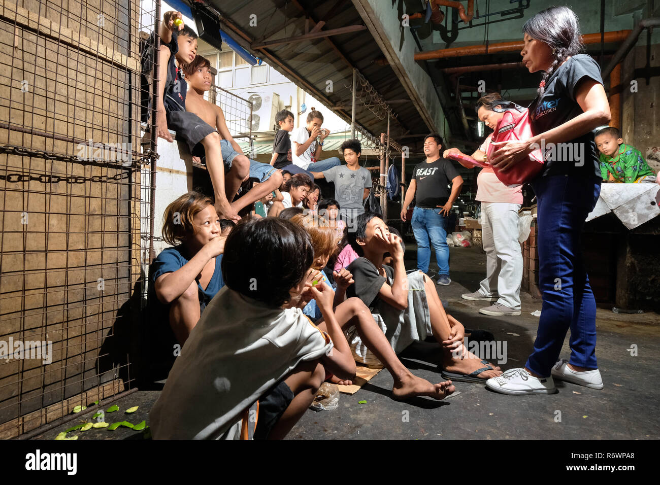 Sozialarbeiter des Kuya Zentrum für Straßenkinder in Kontakt kommen mit heimatlosen Kindern auf einem Markt in Quezon City, Metro Manila, Philippinen zu registrieren. Stockfoto