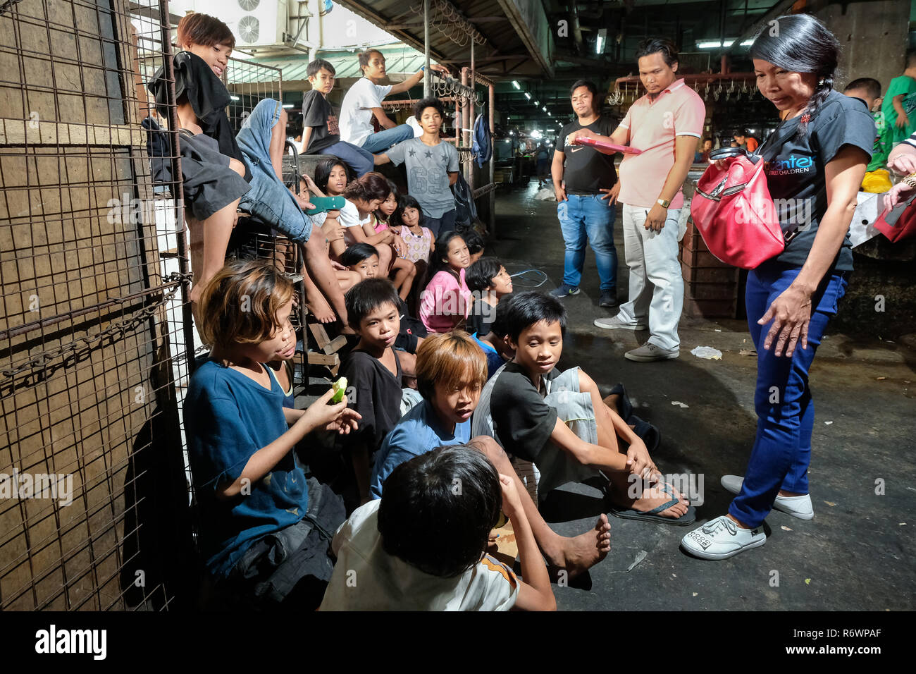 Sozialarbeiter des Kuya Zentrum für Straßenkinder in Kontakt kommen mit heimatlosen Kindern auf einem Markt in Quezon City, Metro Manila, Philippinen zu registrieren. Stockfoto