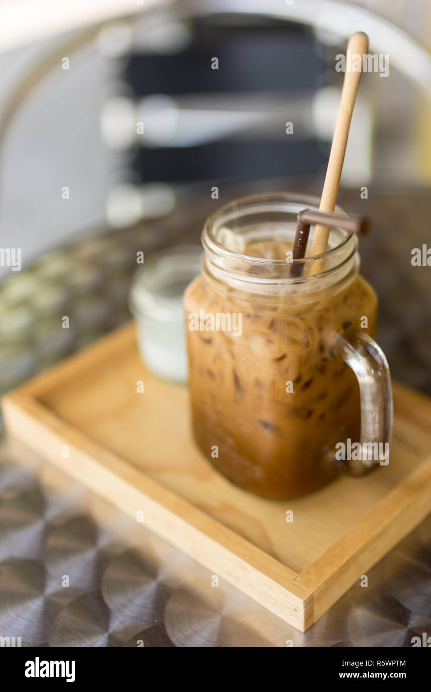 Thai Eiskaffee mit Milch in ein Glas Marmeladenglas auf Holz- Fach und Tisch, Tiefenschärfe konzentrieren. Stockfoto