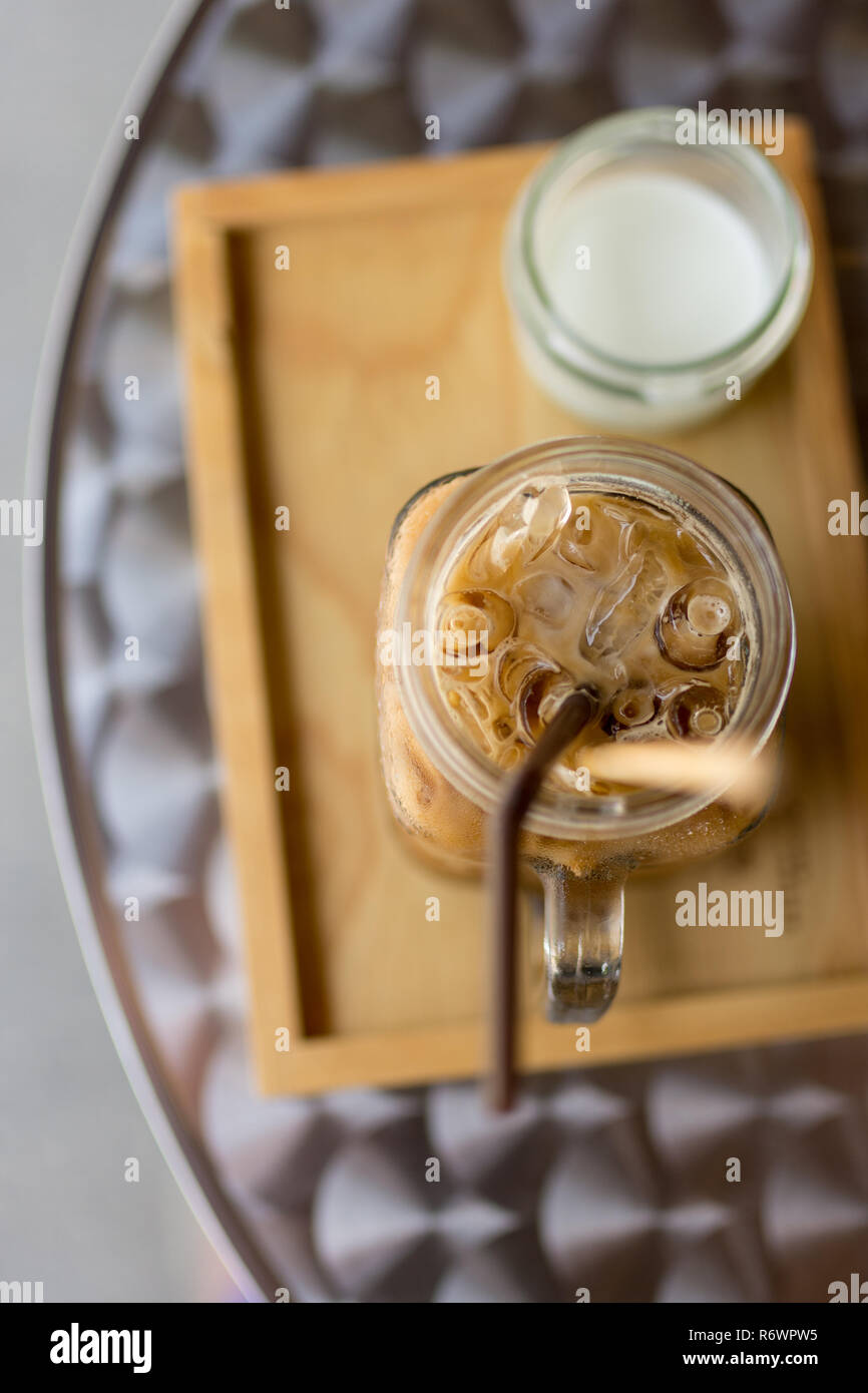 Thai Eiskaffee mit Milch in ein Glas Marmeladenglas auf Holz- Fach und Tisch, Tiefenschärfe konzentrieren. Stockfoto