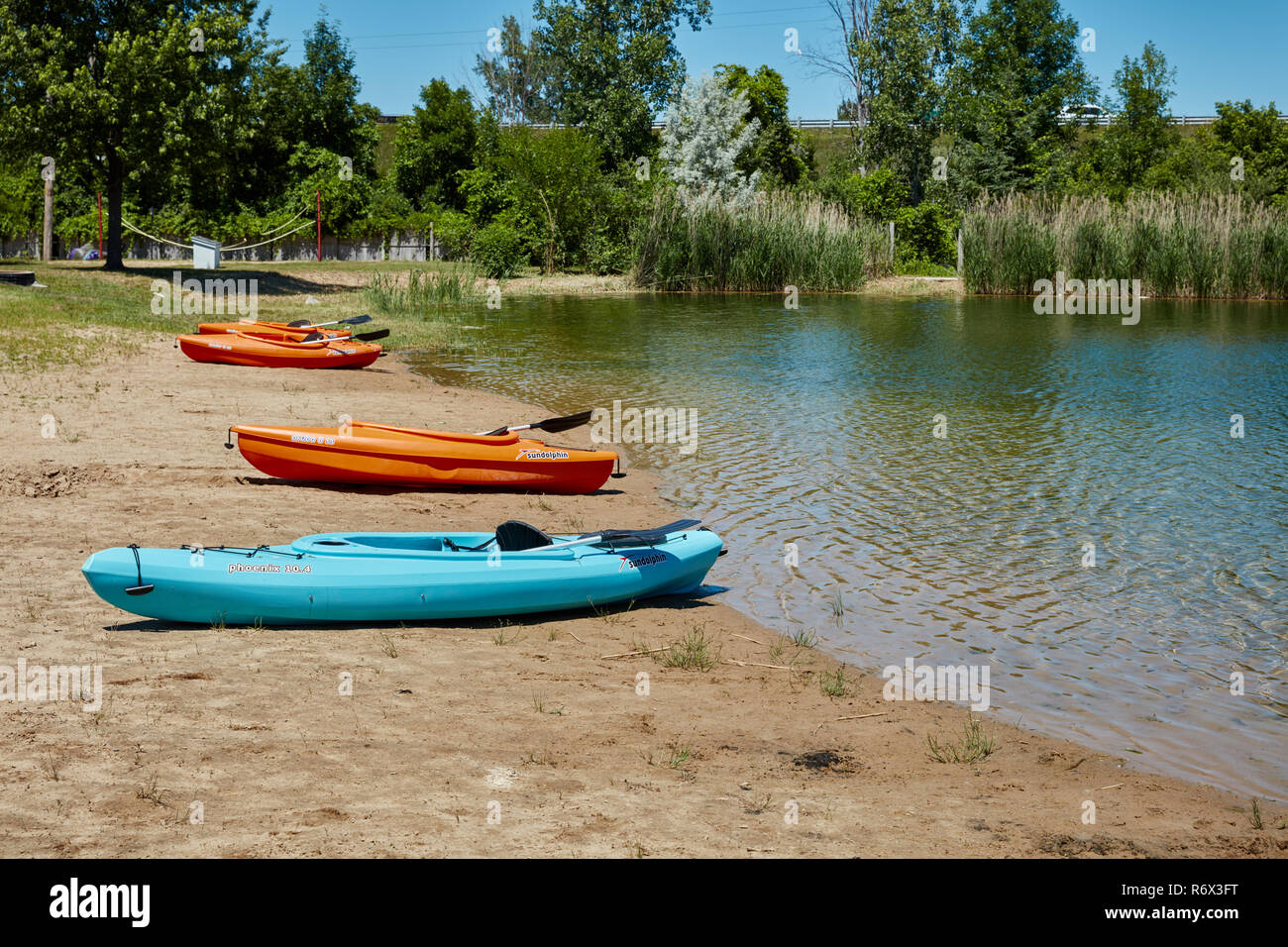 Kajaks aufgereiht auf einen Strand an einem kleinen Teich Stockfoto