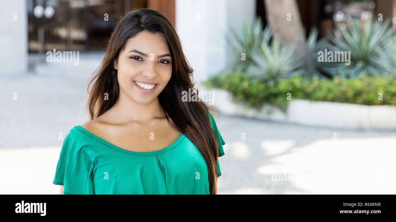 Lachend lateinamerikanischen Frau in grün Shirt im Sommer in der Stadt Stockfoto