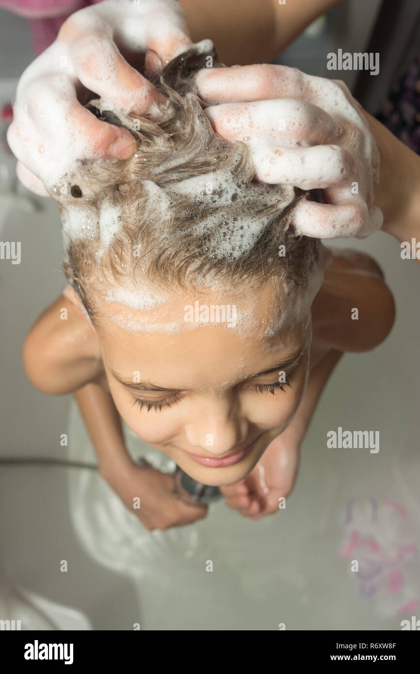 Mom soaped lange Haare des Kindes mit Shampoo und Massagen, die Ansicht von oben Stockfoto