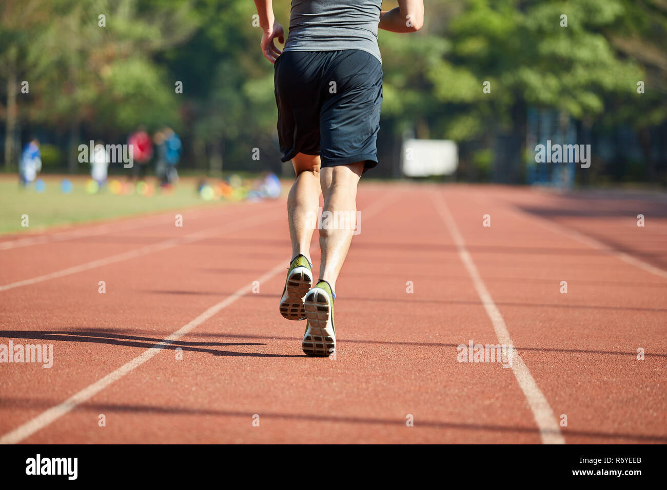 Junge asiatische Läufer laufen auf Schiene, Ansicht von hinten. Stockfoto