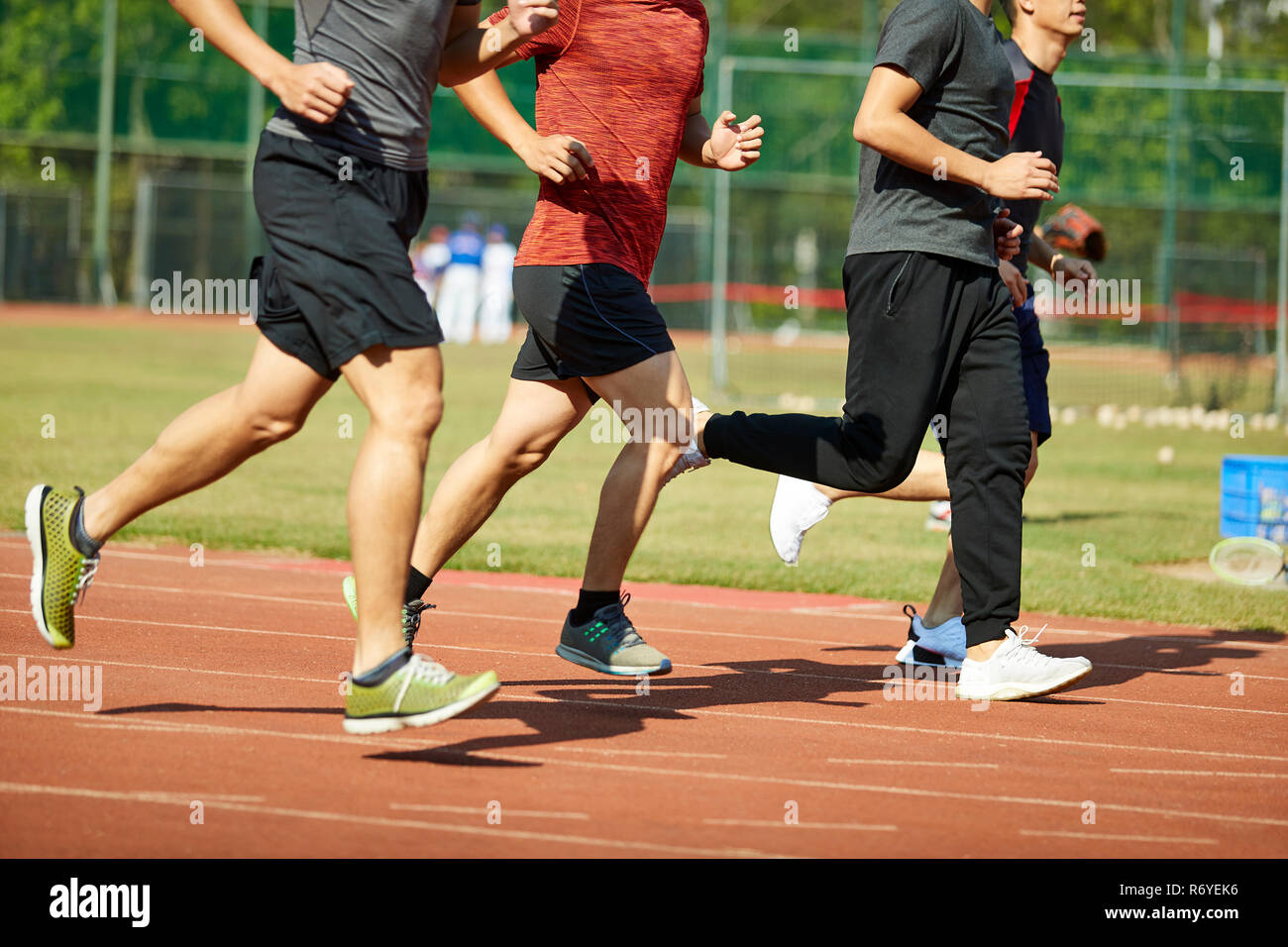 Vier jungen asiatischen Leichtathleten racing gegeneinander konkurrieren. Stockfoto