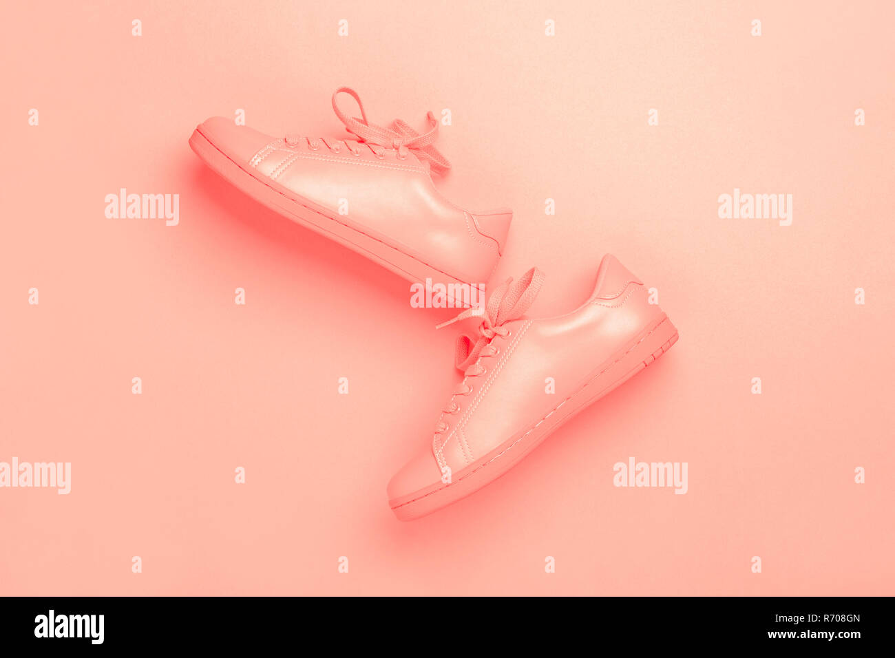 Paar coral Schuhe auf Coral Hintergrund. Trendy lebende Koralle Farbe des Jahres 2019. Schwarzweißbild. Stockfoto