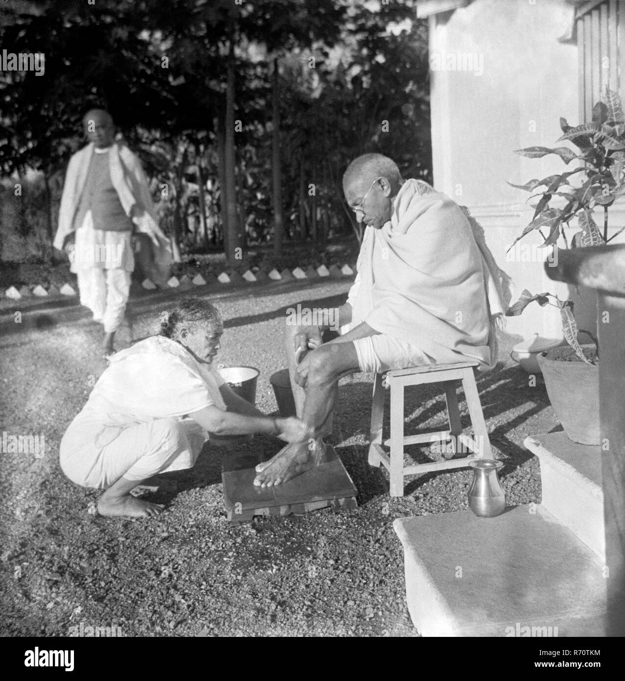 Kasturba Gandhi wäscht ihrem Mann Mahatma Gandhi die Füße, hinter Sardar Vallabhbhai Patel, Bardoli, Gujarat, Indien, 1939, Altes Vintage 1900er Bild Stockfoto