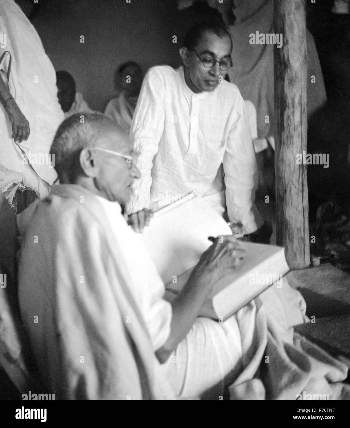 Mahatma Gandhi mit seinem Sekretär Pyarelal Nayar in seiner Hütte in Sevagram Ashram, Wardha, Maharashtra, Indien, 1939, Altes Vintage 1900er Bild Stockfoto